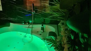 A hot tub with a green light, surrounded by plants. - Spa, sauna, tropical rain sky, complimentary bottle, romantic night  (Macon)