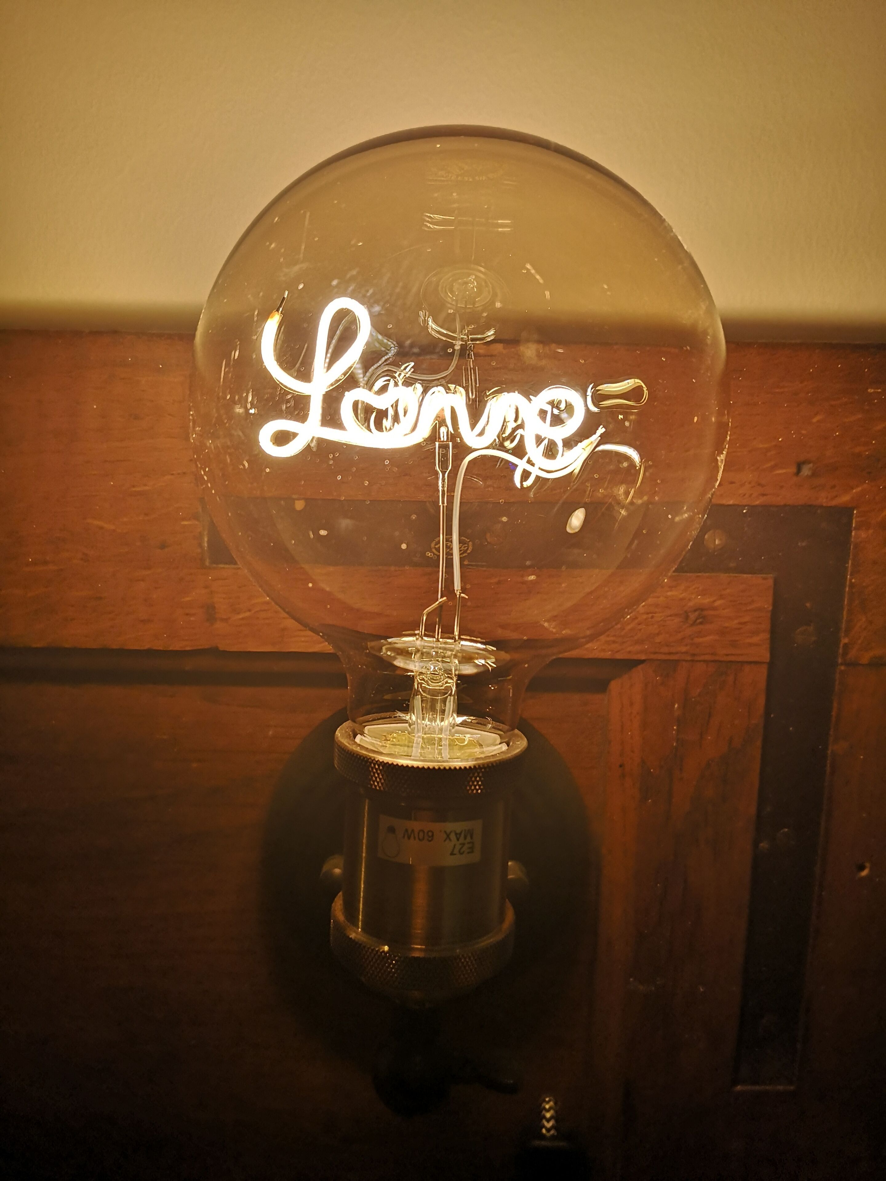 A clear glass globe with the word "Lounge" written inside, mounted on a wooden base.