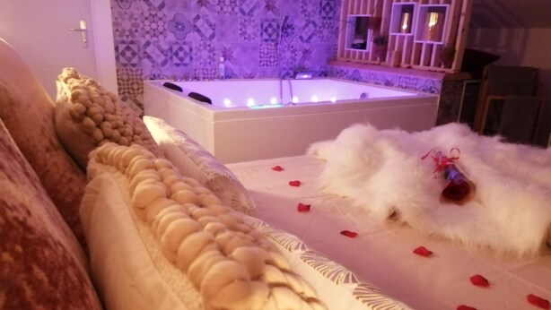 Un dormitorio lujoso con una cama grande, una bañera y un muro decorativo.