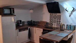 Cocina compacta con tragaluz, microondas, lavabo y comedor con sillas.