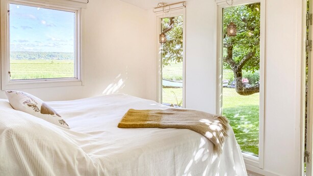 A bedroom with a large window, a bed with a white bedspread, and a view of a green landscape. - 1 bedroom nice home in Varberg (Varberg)