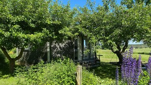 A rustic wooden cabin surrounded by lush greenery and flowering plants. - 1 bedroom nice home in Varberg (Varberg)