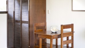Una habitación con un armario de madera, una mesa de madera con un cuenco y una silla.