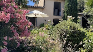 A building with a balcony and a patio area with an umbrella. - Green oasis with magnificent sea views, center within walking distance, including housekeeper (Saint-Tropez)