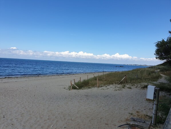 A sandy beach with a wooden fence and a utility box.