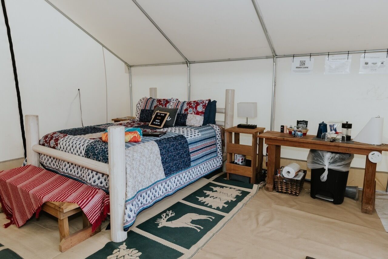 A cozy tented room with a bed, a wooden table, and a bench.
