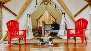 Eine Zelthütte mit zwei roten Stühlen vor einem zentralen Feuerkorb.