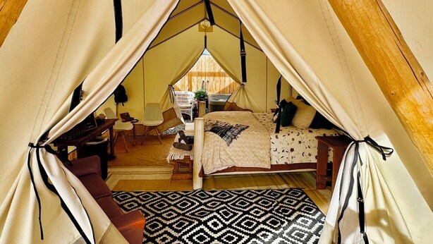 Eine gemütliche Zelthütte mit Bett, Schreibtisch und Stuhl.
