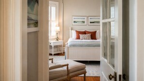 A bedroom with a bed, bedside table, lamp, and a view of the outdoors. - The Edenton Collection-Captain's Quarters Inn (Edenton)