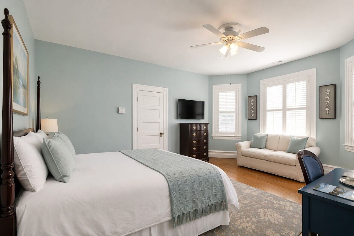 A bedroom with a bed, dresser, TV, and a window.
