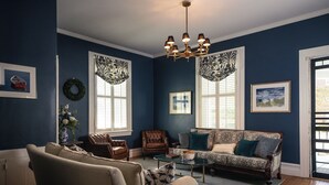 A living room with a sofa, armchairs, a coffee table, and a chandelier. - The Edenton Collection-Captain's Quarters Inn (Edenton)