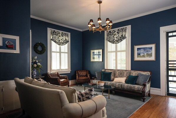 A living room with a sofa, armchairs, a coffee table, and a chandelier.