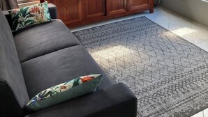 Quarto com sofá, um armário de madeira e vista para um jardim através de uma janela.