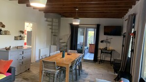 Uma sala de estar acolhedora com uma mesa de jantar de madeira, um sofá e uma TV na parede.