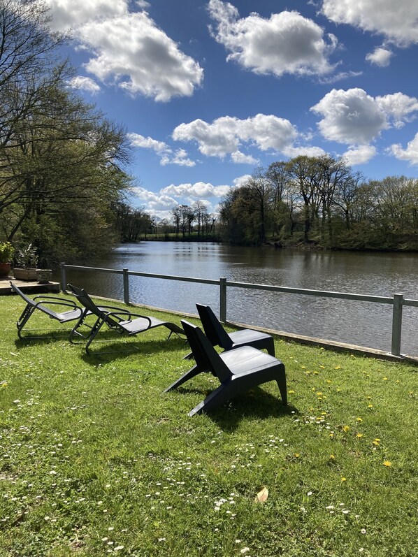 A riverside park with chairs and a fence.