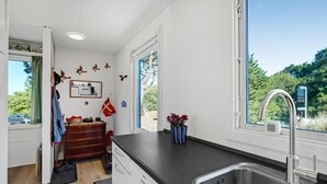 Moderni keittiö, jossa on suuri ikkuna, sisäänrakennettu pesuallas ja puinen lipasto.