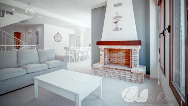 A modern living room with a white sofa, a white coffee table, and a brick fireplace. - PUSHE Village Playa Granada Beach & Golf 2 (Motril)