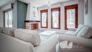 A modern living room with a fireplace, large windows, and a chandelier. - PUSHE Village Playa Granada Beach & Golf 2 (Motril)