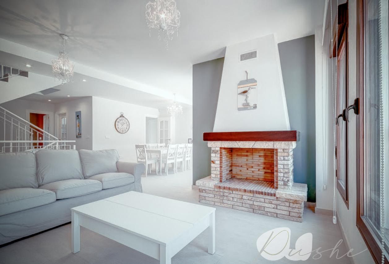 Una sala de estar moderna con un sofá blanco, una mesa de centro blanca y una chimenea de ladrillo.