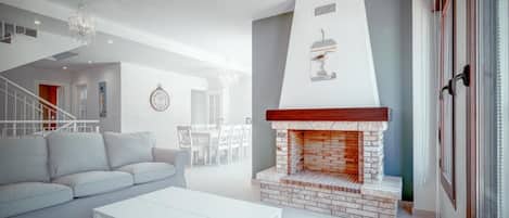 Una sala de estar moderna con un sofá blanco, una mesa de centro blanca y una chimenea de ladrillo.
