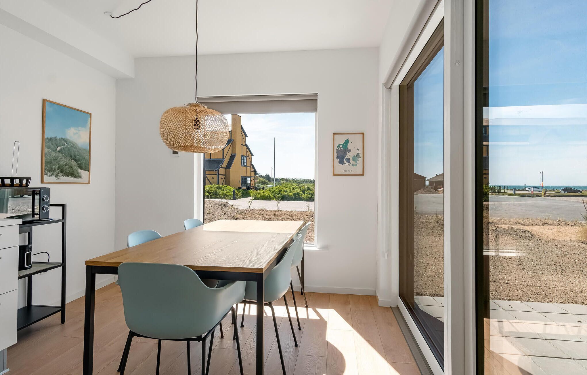 Una cuina moderna amb zona de menjador, grans finestres i vista a un edifici en construcció.