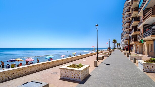 A coastal promenade with a clear view of the sea, a tiled walkway, and a row of multi-story buildings with balconies. - 3 bedroom cozy apartment in Sueca (Sueca)