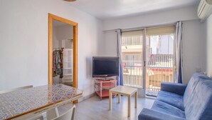 A living room with a TV, a sofa, a dining table, and a balcony with a railing. - 3 bedroom cozy apartment in Sueca (Sueca)