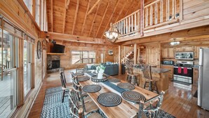 Une cabane en bois spacieuse, dotée d’un grand espace repas, d’une cuisine et d’un salon confortable.