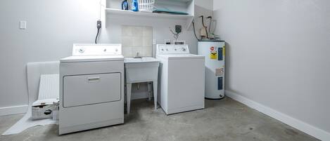 A laundry room with a washer, dryer, and stacked laundry baskets.
