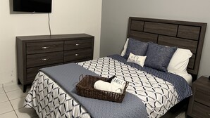 A bedroom with a bed, a dresser, a television, and a nightstand.