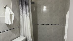 A bathroom with a shower, toilet, and sink.