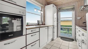 Een moderne keuken met witte kasten, een inbouwoven en een groot raam voor natuurlijk licht.