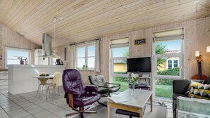 Een ruime woonkamer met een keuken, eettafel en zitplaatsen.