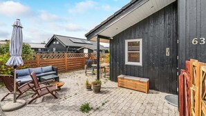 Een terras met buitenmeubilair, een houten bankje en een bloempot.