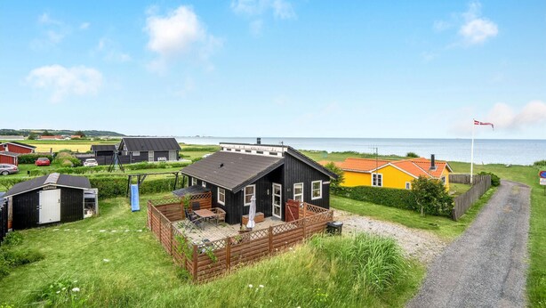Een kustpand met een houten terras, een klein terrasje en uitzicht op zee.