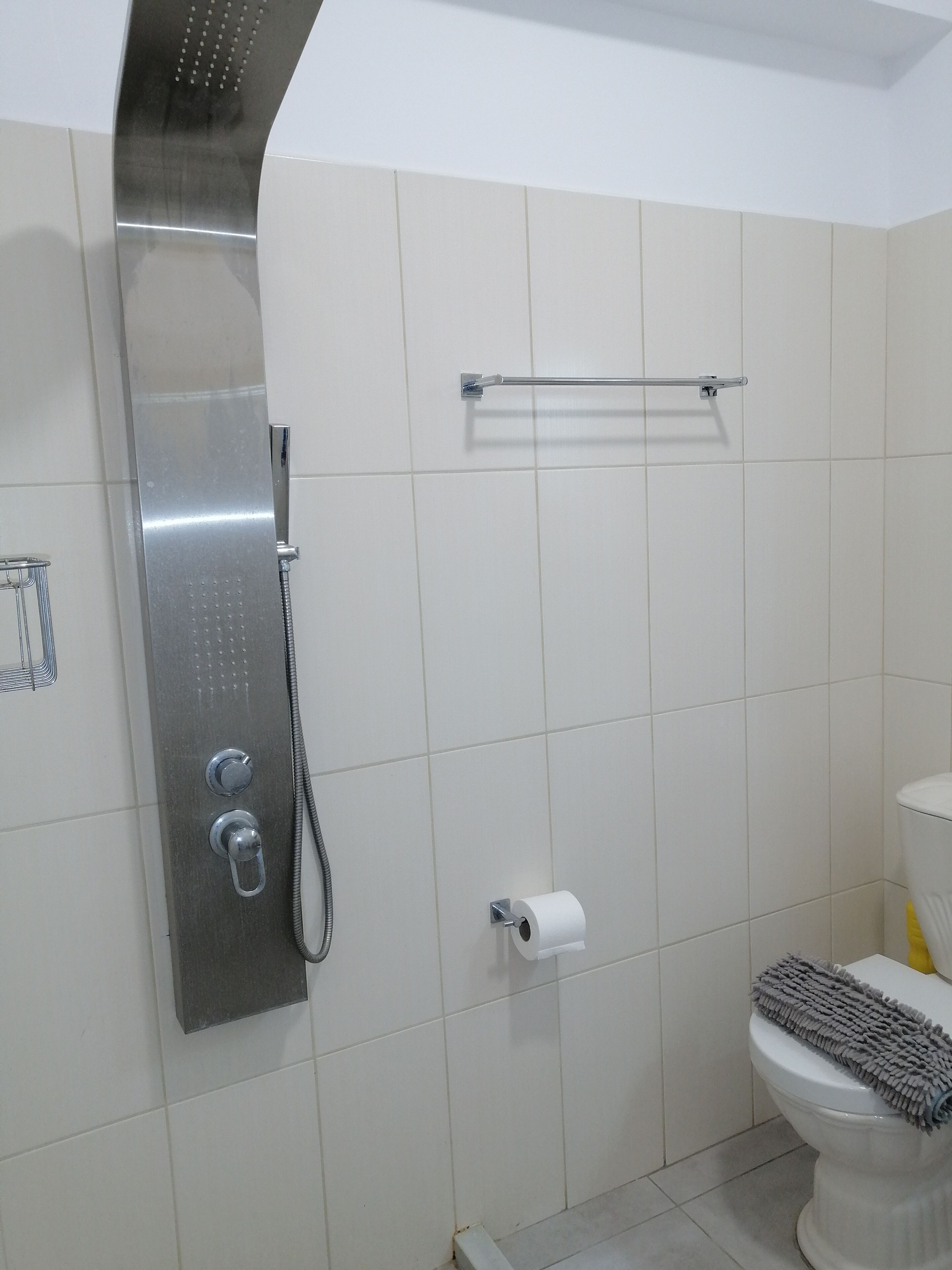 Un baño con ducha, inodoro y toallero.