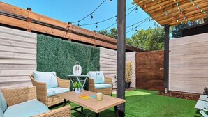 Un patio con mobiliario de mimbre, una mesa y una pared verde.