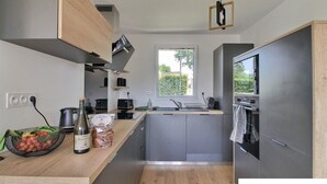 A modern kitchen with a central island, built-in appliances, and a window providing natural light. - Beg-Meil House ****, 300m from beaches and village (FOUESNANT)