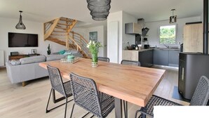 A modern kitchen with a wooden staircase, a dining area with a large table and chairs, and a built-in stove. - Beg-Meil House ****, 300m from beaches and village (FOUESNANT)