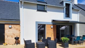 A modern house with a patio area featuring outdoor furniture and a barbecue. - Beg-Meil House ****, 300m from beaches and village (FOUESNANT)