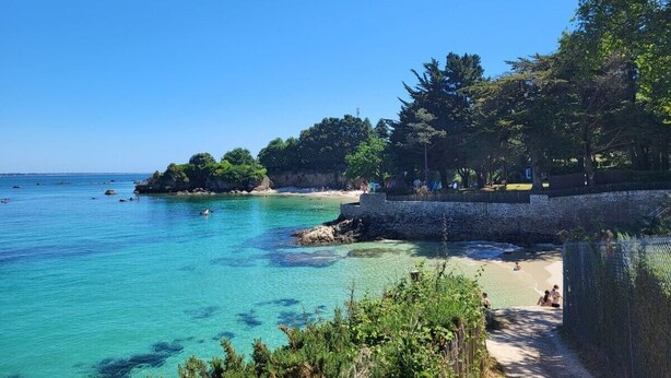 A coastal beach scene with clear turquoise water, a stone wall, and lush greenery. - Beg-Meil House ****, 300m from beaches and village (FOUESNANT)