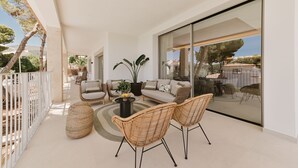 A modern, open-plan living area with a sofa set, two wicker chairs, a coffee table, and a potted plant. - Luxury Villa. Heated pool. Sea & Mountain views (Cas Català)