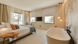 Une chambre moderne avec un grand lit, une baignoire et un téléviseur.