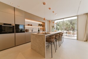 Una cucina moderna con isola centrale, sgabelli da bar e vista su un patio esterno.