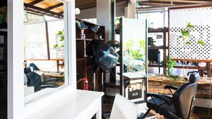 A salon with a modern interior, including a hairdryer, shelves with hair products, and a view through a window. - The Blue Suites & Spa (La Fortuna)