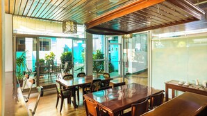 A restaurant with wooden tables and chairs, a glass wall, and a view of the outside. - The Blue Suites & Spa (La Fortuna)