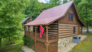 A wooden cabin with a balcony, stone foundation, and a red roof. - Cozy2 BD Easily Accessible Cabin! Quiet community short drive to all attractions (Pigeon Forge)