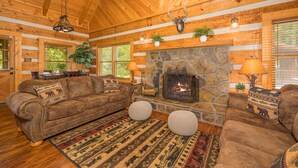 A cozy log cabin interior with a stone fireplace, wooden walls, and a rustic decor. - Cozy2 BD Easily Accessible Cabin! Quiet community short drive to all attractions (Pigeon Forge)