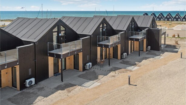 A row of beach huts with sloped roofs, wooden facades, and glass balconies.