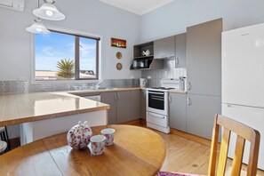 Una cocina moderna con una mesa de comedor de madera, un refrigerador, una estufa y una ventana con vistas a palmeras.